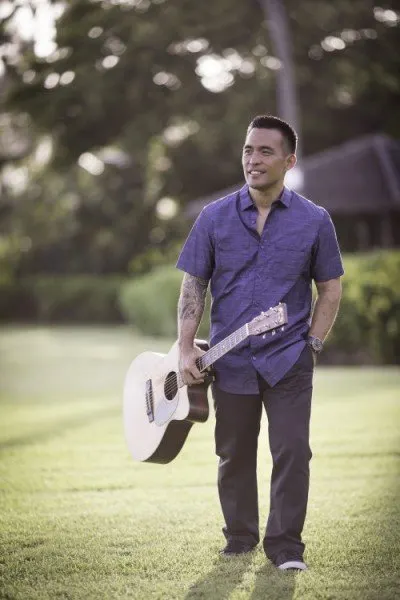 Dayton standing on a lawn holding his guitar